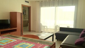 Ein Wohnzimmer mit einer Couch, einem Glastisch und einem Fernseher.