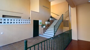 A staircase with a green railing, beige walls, and a tiled floor. - Els Pins apartment in Estartit (Estartit)