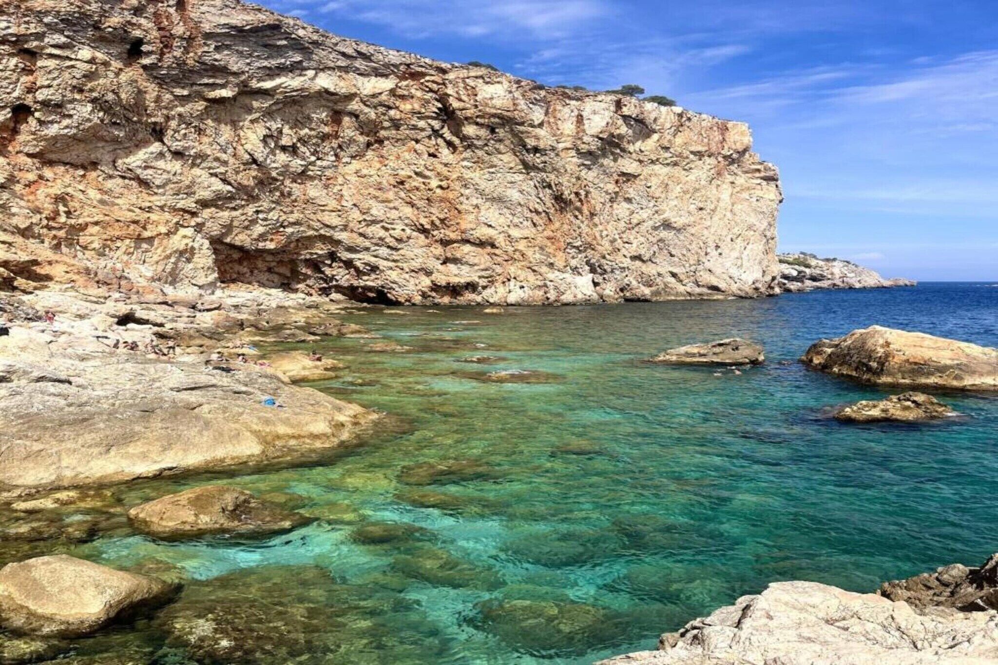 A rocky coastline with clear turquoise water and large boulders.