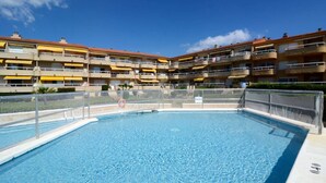 A swimming pool surrounded by a multi-story building with balconies.