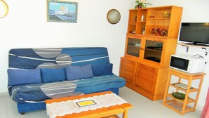 A living room with a blue sofa, wooden cabinet, and a small table with a bowl.