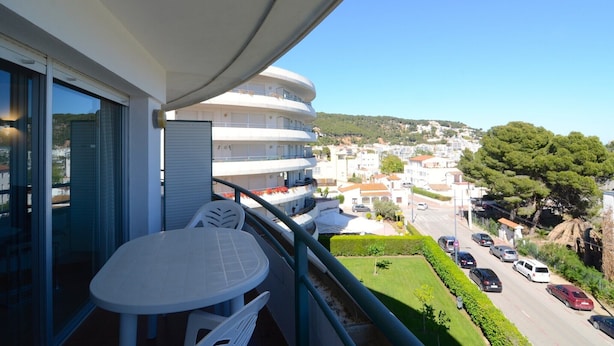 Ein Balkon mit Tisch und Stühlen, mit Blick auf eine Straße mit Autos und Gebäuden.