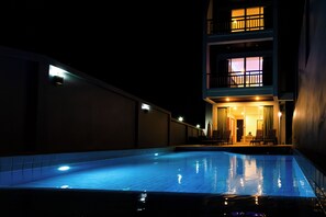 A swimming pool at night with a building in the background.