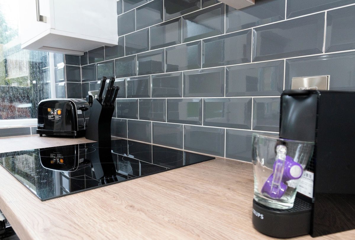 A modern kitchen with a black induction cooktop, a toaster, and a coffee maker on the counter.