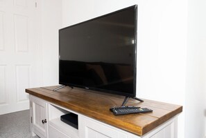Un televisor de pantalla plana sobre un mueble de madera con un control remoto.