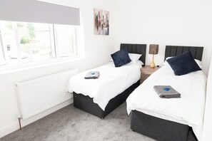Une chambre d’hôtel avec deux lits, un radiateur, une fenêtre et un tableau au mur.