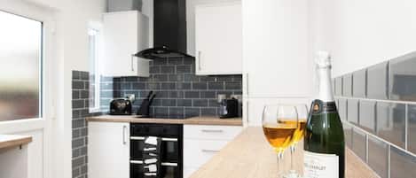 A modern kitchen with white cabinets, a black range hood, and a wooden countertop.