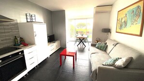 A compact living space with a kitchenette, a dining area, and a sofa. - "L'Océane" Studio sea view-climate-wifi-parking (La Ciotat)