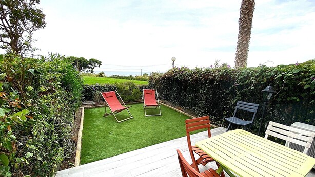A patio with a table and chairs, a lawn, and a view of the sea. - "L'Océane" Studio sea view-climate-wifi-parking (La Ciotat)