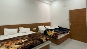 A bedroom with two beds, a ceiling fan, and a wooden wardrobe. - Dev Residency NCR Wale (Danta Ramgarh)