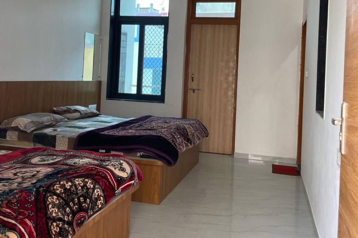 A bedroom with two beds, a ceiling fan, a window, and an air conditioning unit.