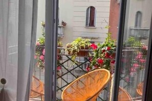 Un balcone con sedie in vimini e piante in vaso.