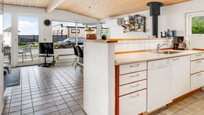 Une cuisine moderne avec des meubles blancs, un plafond en bois et un grand îlot central doté d’un évier.