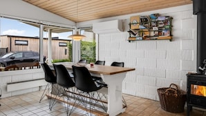 Une cuisine moderne avec un îlot central, des chaises noires, un plafond en bois et une cuisinière noire.