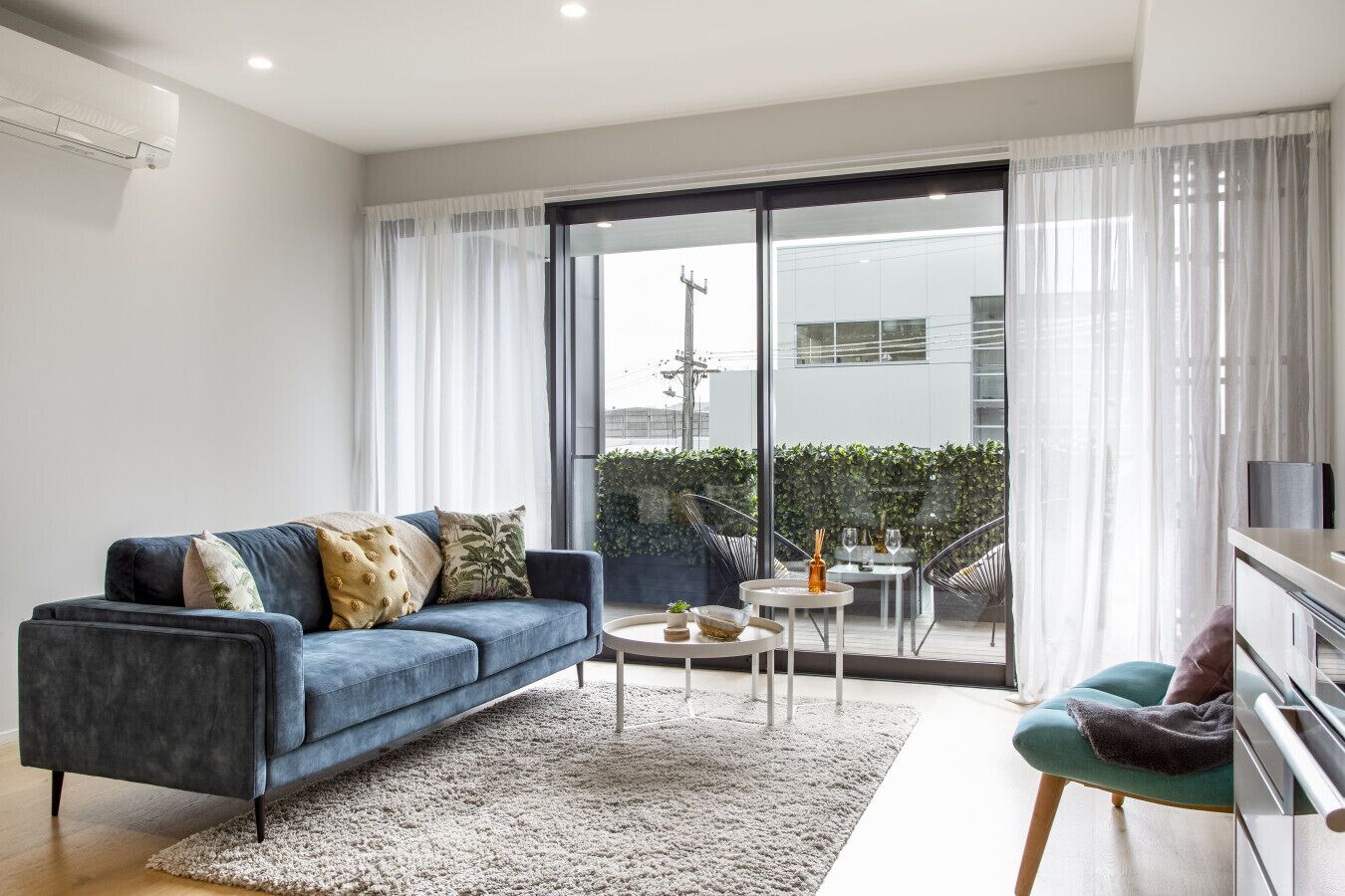 A modern living room with a blue sofa, a small round table, and a green chair.