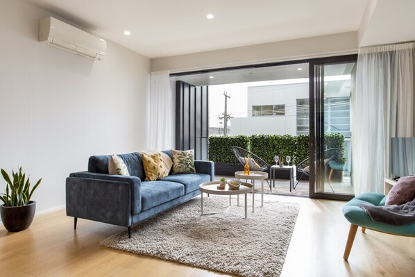 A modern living room with a blue sofa, a coffee table, and a potted plant.