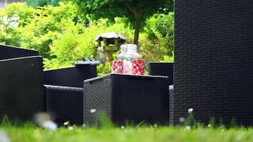 Mobilier en osier pour l’extérieur, avec une bouteille en verre et un gobelet rouge et blanc.