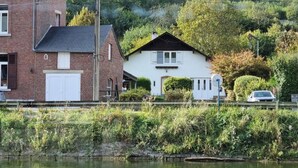 Udsigt over en boligområde ved en flod, med huse, en bil og en bro.