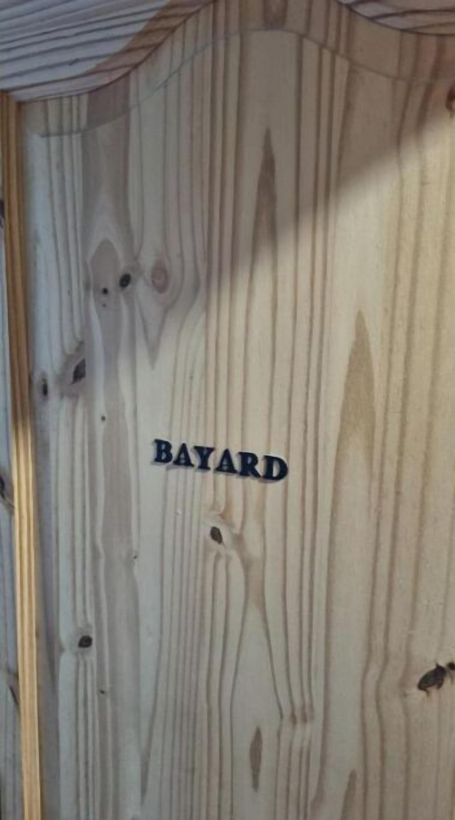 Een houten wand met de tekst 'BAYARD'.