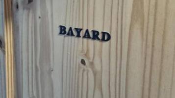 Een houten wand met de tekst 'BAYARD'.