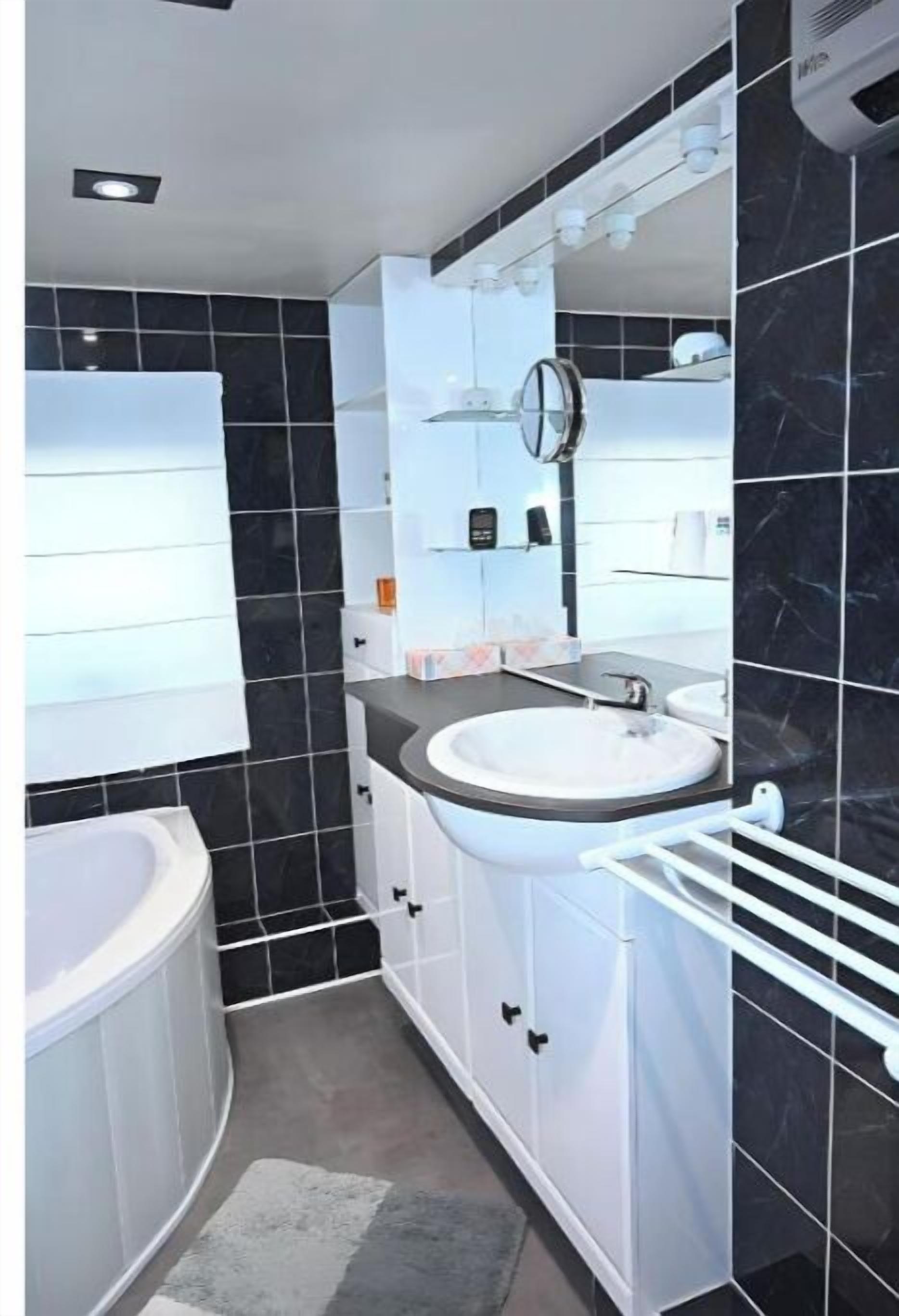 A modern bathroom with a white vanity, a large sink, and a mirror.