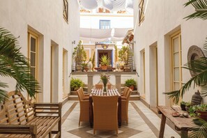 Un patio con un banco de madera, sillas de mimbre y una mesa con un florero.