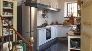 Eine Küche mit einem Edelstahl-Kühlschrank, weißen Schränken und einer Holztreppe.