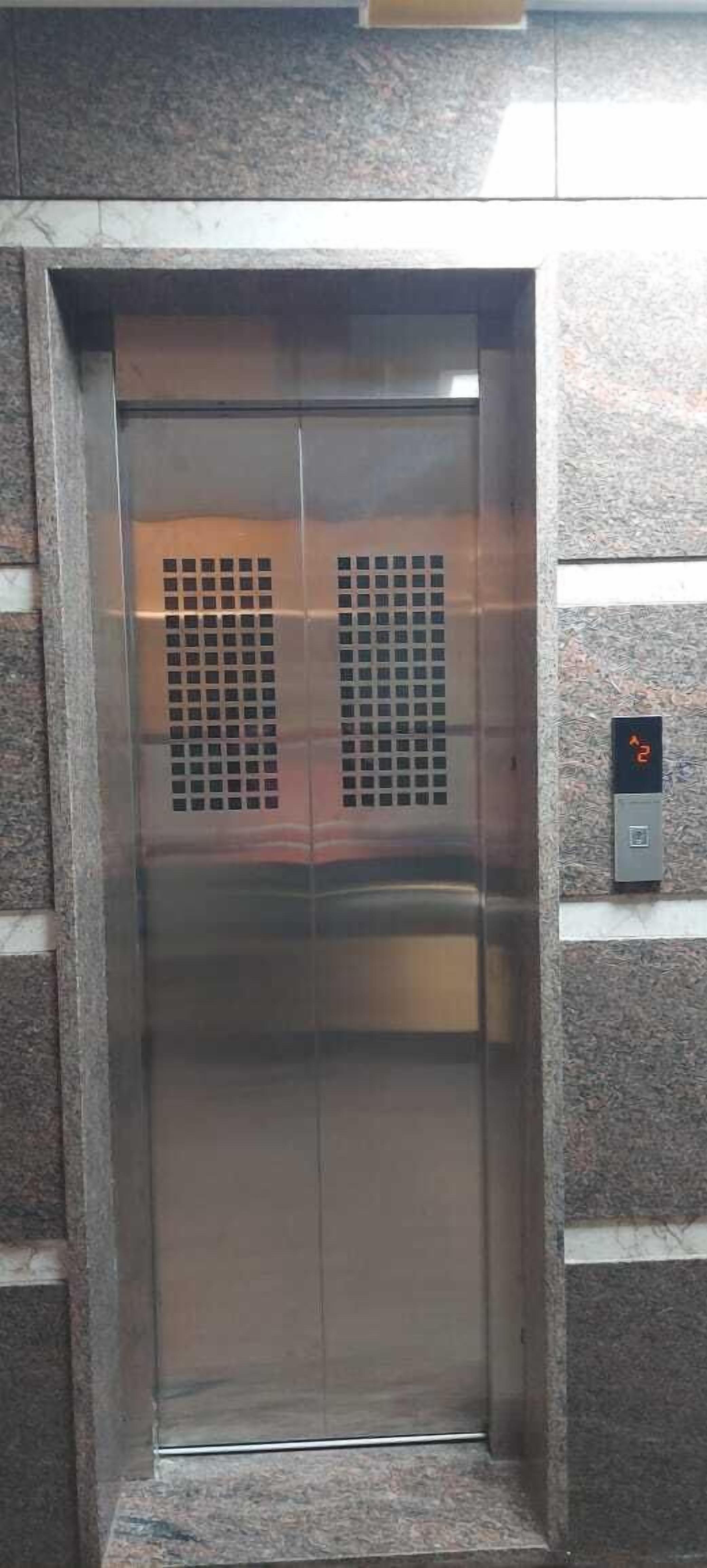 A metallic elevator door with a control panel to the right.