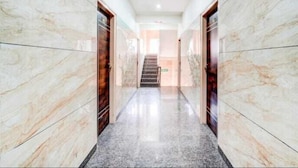 A hallway with marble walls and a polished floor, leading to a staircase. - SGR Paradise (Bengaluru)