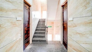 A marble-floored hallway with a staircase leading to a door labeled "Lobby". - SGR Paradise (Bengaluru)