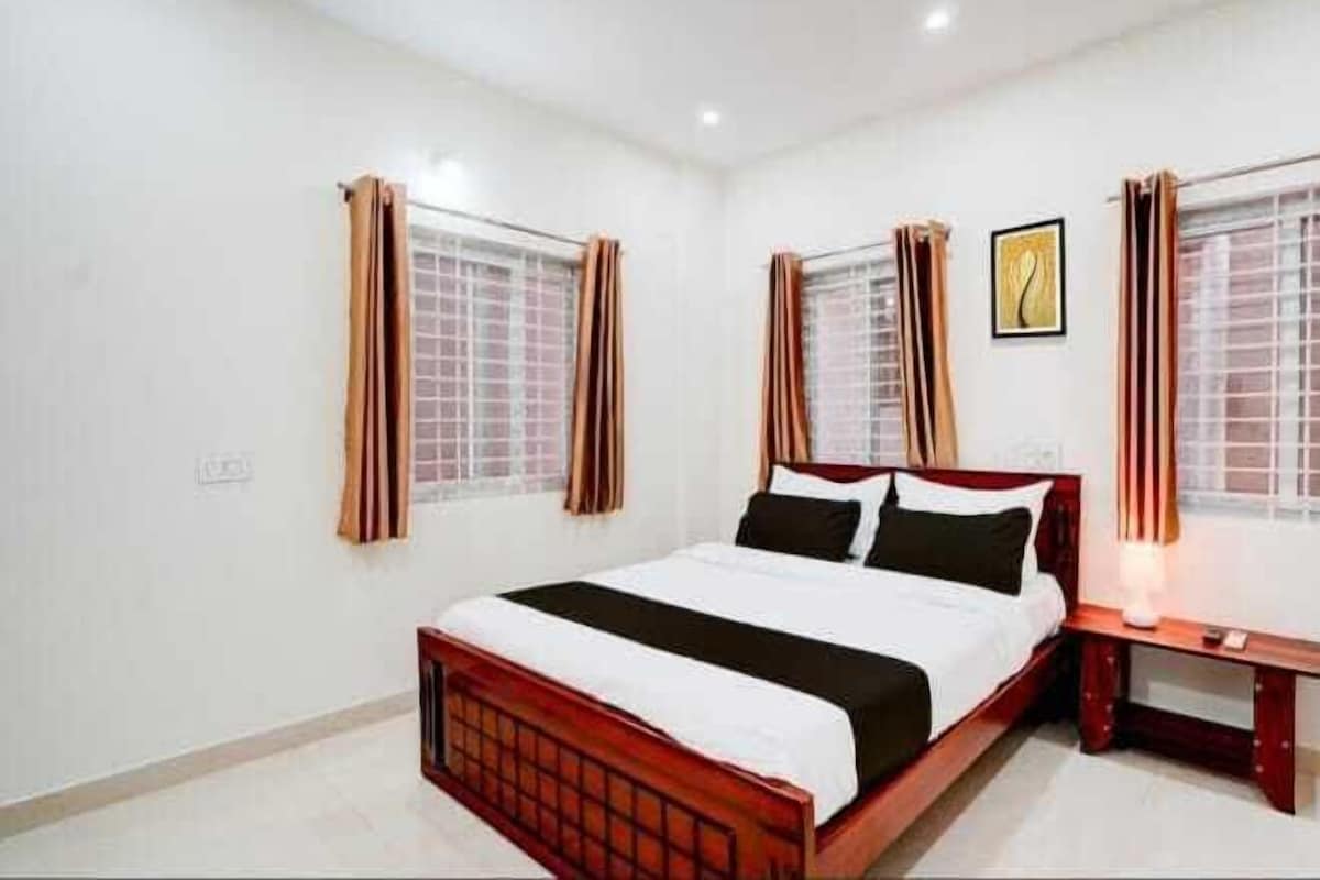 A bedroom with a wooden bed, white bedding, and curtains on windows.