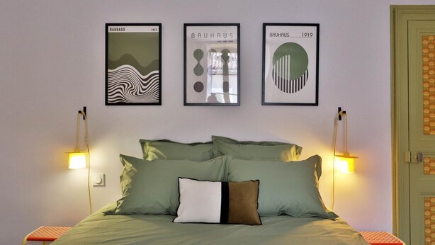 A bed with green bedding, a white pillow with a brown stripe, and three framed artworks on the wall above. - Room POP - Private bathroom (Montbron)