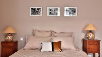 A bedroom with a bed, two nightstands, and three framed pictures on the wall.
