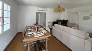 A dining area with a wooden table set for four, a sofa, and a fireplace.