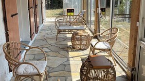 A covered outdoor seating area with wicker furniture and a stone floor.