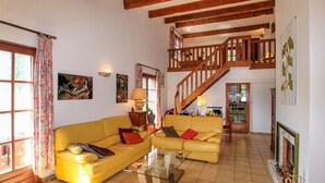 A spacious living room with a yellow sofa, a glass coffee table, and a wooden staircase leading to an upper level. - Gorgeous home in Saint Sernin (Saint Sernin)