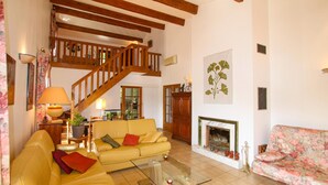 A spacious living room with a wooden staircase, a fireplace, and a floral sofa. - Gorgeous home in Saint Sernin (Saint Sernin)