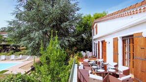 A patio area with outdoor seating, a pool, and a building with wooden shutters. - Gorgeous home in Saint Sernin (Saint Sernin)