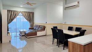 A modern living room with a sofa, dining table, chairs, and a ceiling fan. - Twin Galaxy Residences by Widebed JB (Johor Bahru)