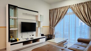 A modern living room with a flat-screen TV, a glass coffee table, and a brown leather sofa. - Twin Galaxy Residences by Widebed JB (Johor Bahru)