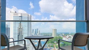 A balcony with two wicker chairs and a small round table, overlooking a cityscape with high-rise buildings and construction sites. - Twin Galaxy Residences by Widebed JB (Johor Bahru)