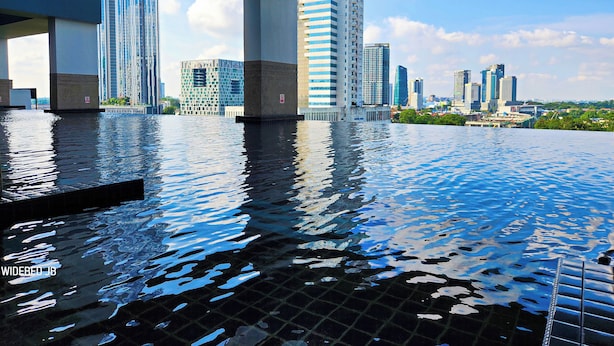 An indoor infinity pool with a cityscape view, modern architecture, and clear skies. - Twin Galaxy Residences by Widebed JB (Johor Bahru)