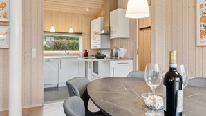 A modern kitchen with white cabinets, a marble countertop, and a dining area with a table and chairs.