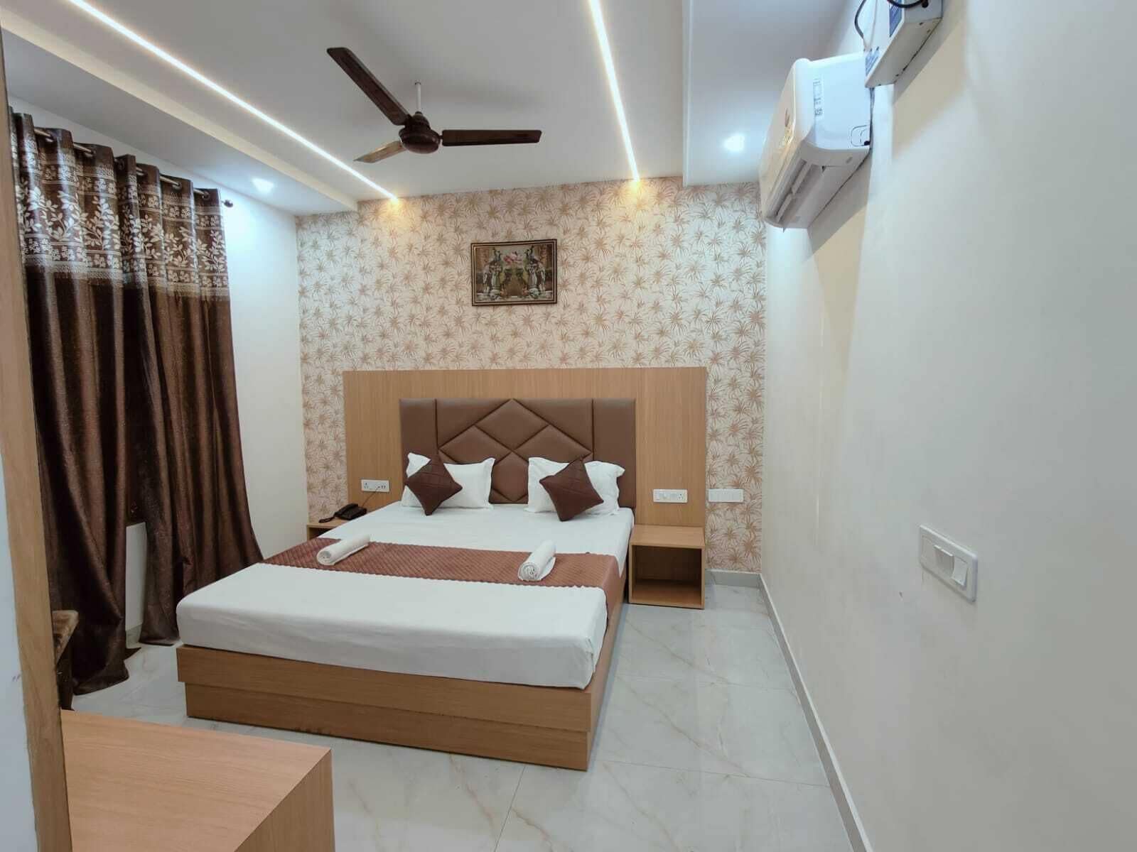 A neatly arranged bedroom with a bed, a ceiling fan, an air conditioning unit, and a patterned wallpaper.