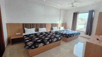 A hotel room with two beds, a wooden headboard, a desk, and a ceiling fan.