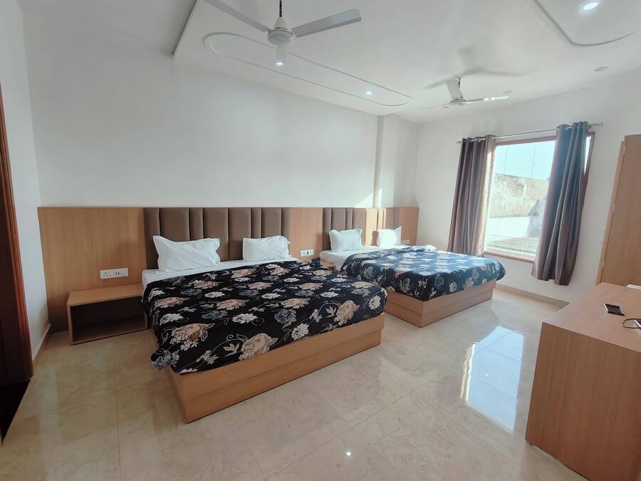 A hotel room with two beds, a wooden headboard, a desk, and a ceiling fan.