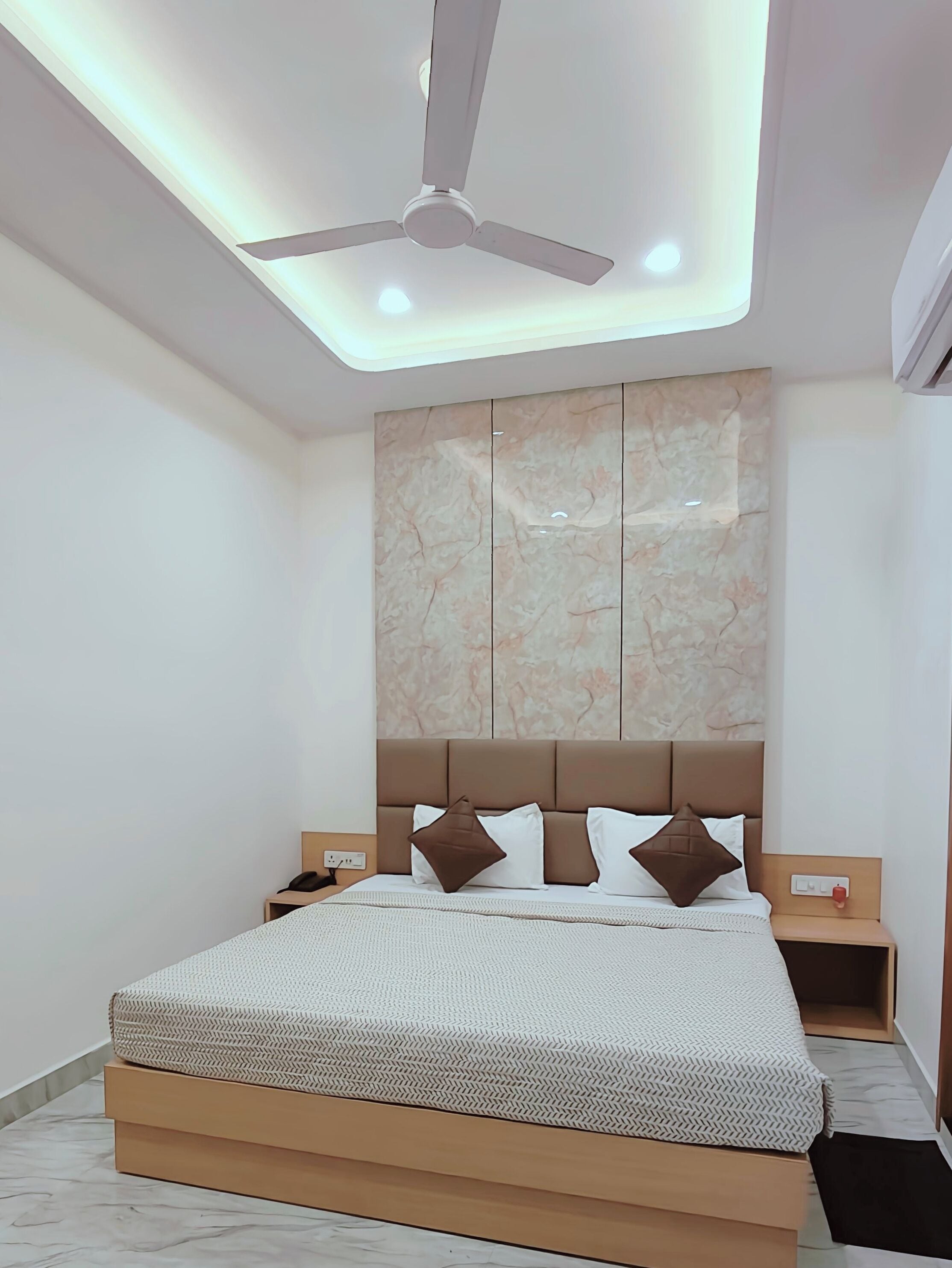 A modern bedroom with a bed, nightstands, a ceiling fan, and a marble-patterned headboard.