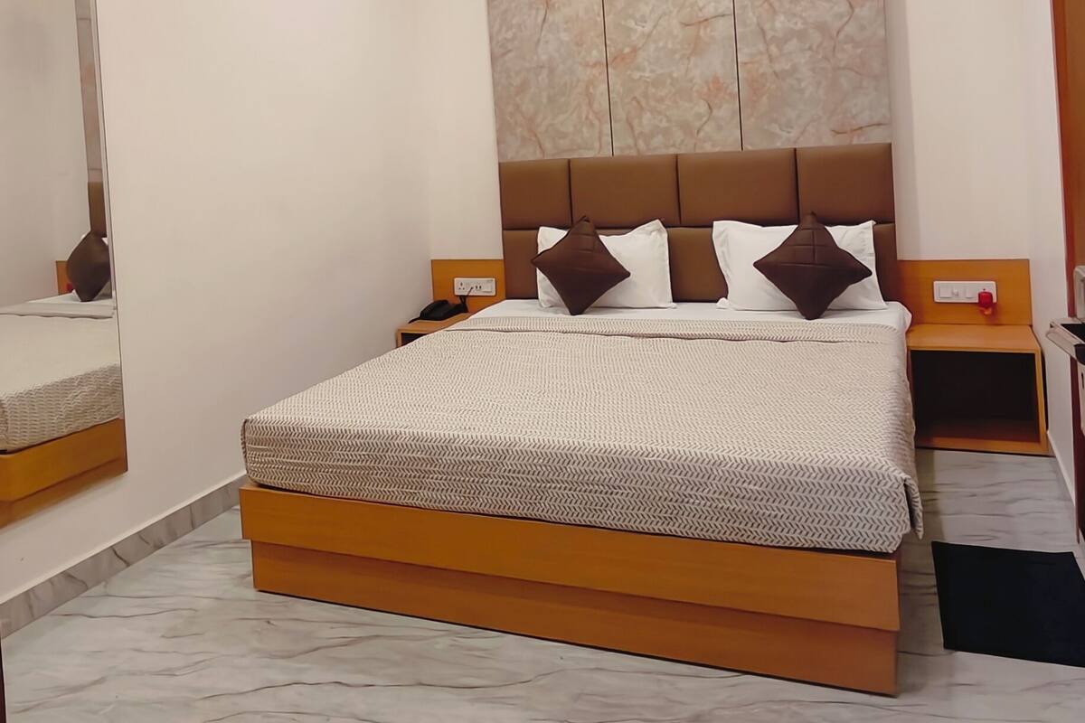 A modern bedroom with a bed, ceiling fan, air conditioning unit, and marble flooring.