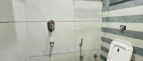 Ein kleines Badezimmer mit Toilette, Dusche und einem blauen Mülleimer.