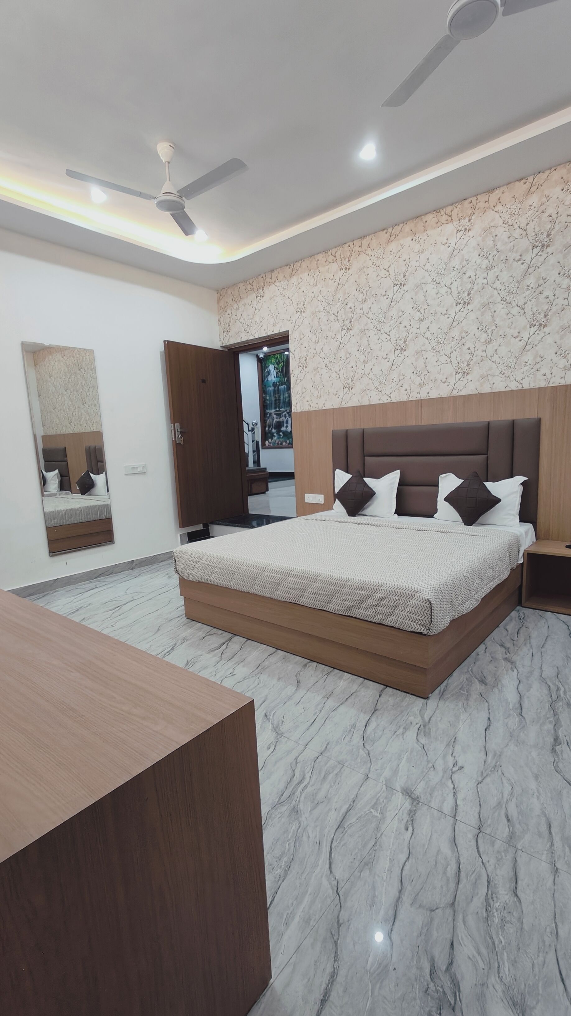 A modern bedroom with a large bed, a ceiling fan, and a marble floor.